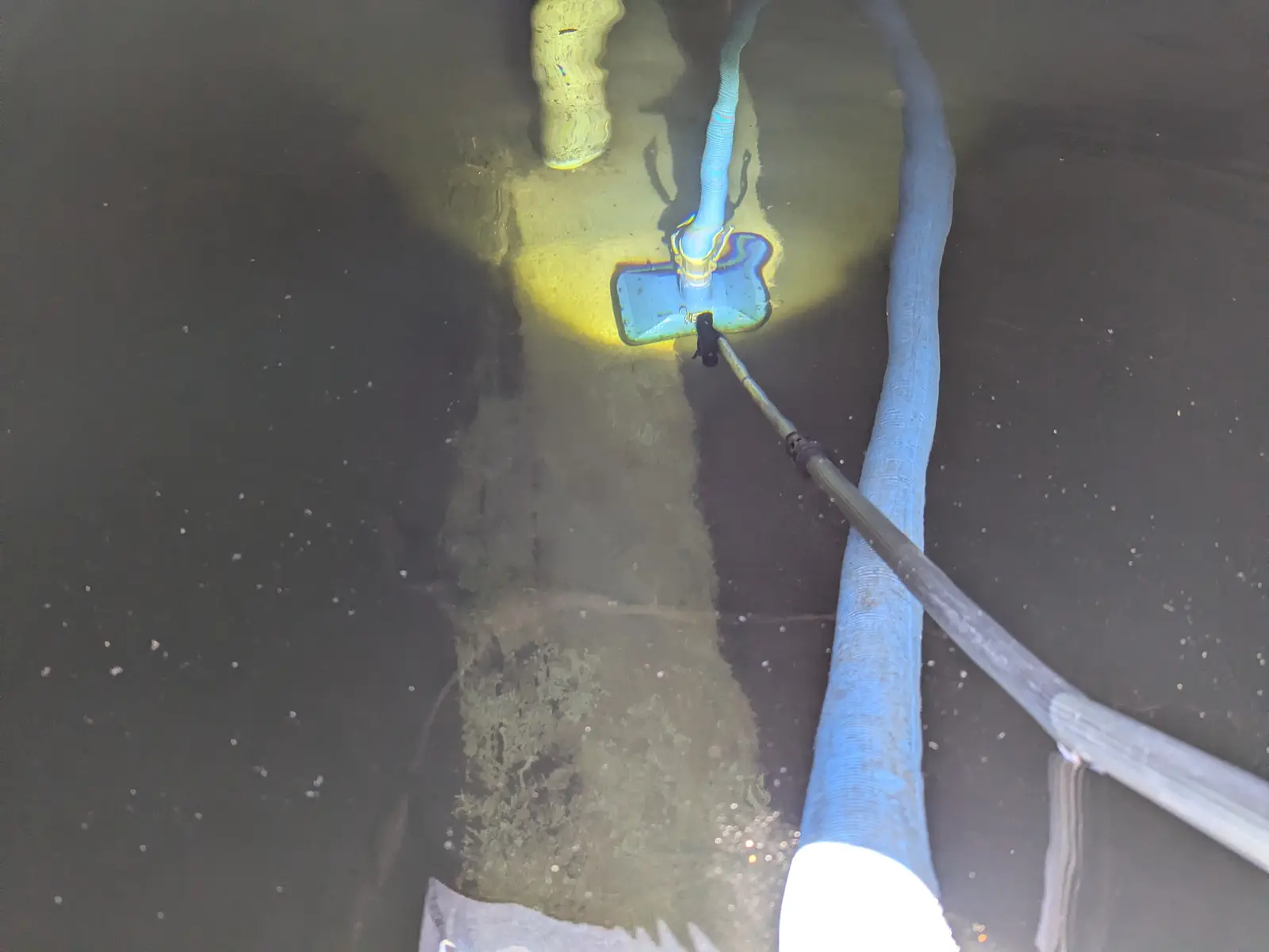 Vacuum cleaning a concrete water tank with brush and suction hose
